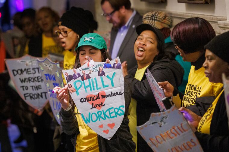 Aurora Muñoz, Pennsylvania organizing manager with National Workers Alliance, holds a shield with images of supportive members of Philadelphia City Council.  National Domestic Workers Alliance was at a Council session, supporting an anti-retaliation bill for workers.