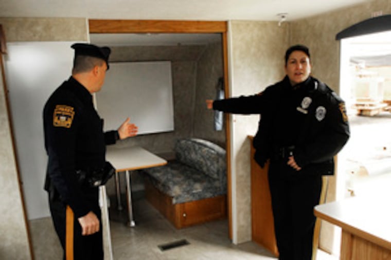 Lower Makefield Police Officers Michael Pell and Denise Siano show off the department's new mobile command trailer - a recycled FEMA home.