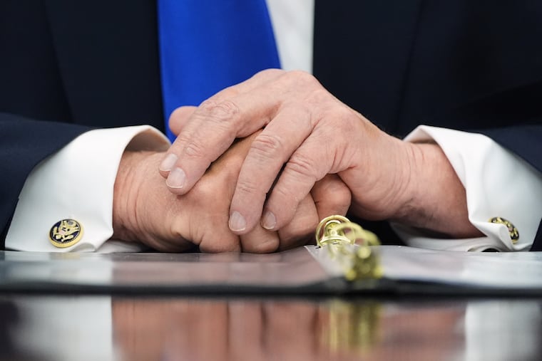 President Donald Trump clasps his hands on the Resolute Desk as he speaks before signing an executive order regarding retirement savings in the Oval Office of the White House last week.
