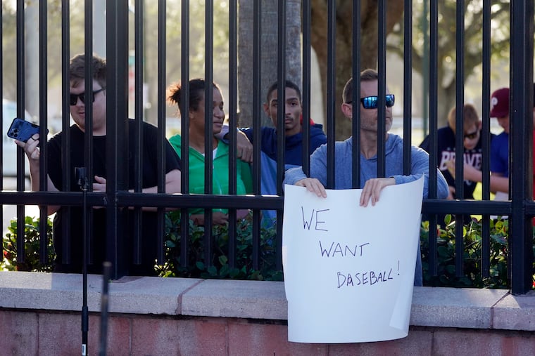Baseball fans watch as commissioner Rob Manfred speaks during a news conference on Tuesday in Jupiter, Fla.