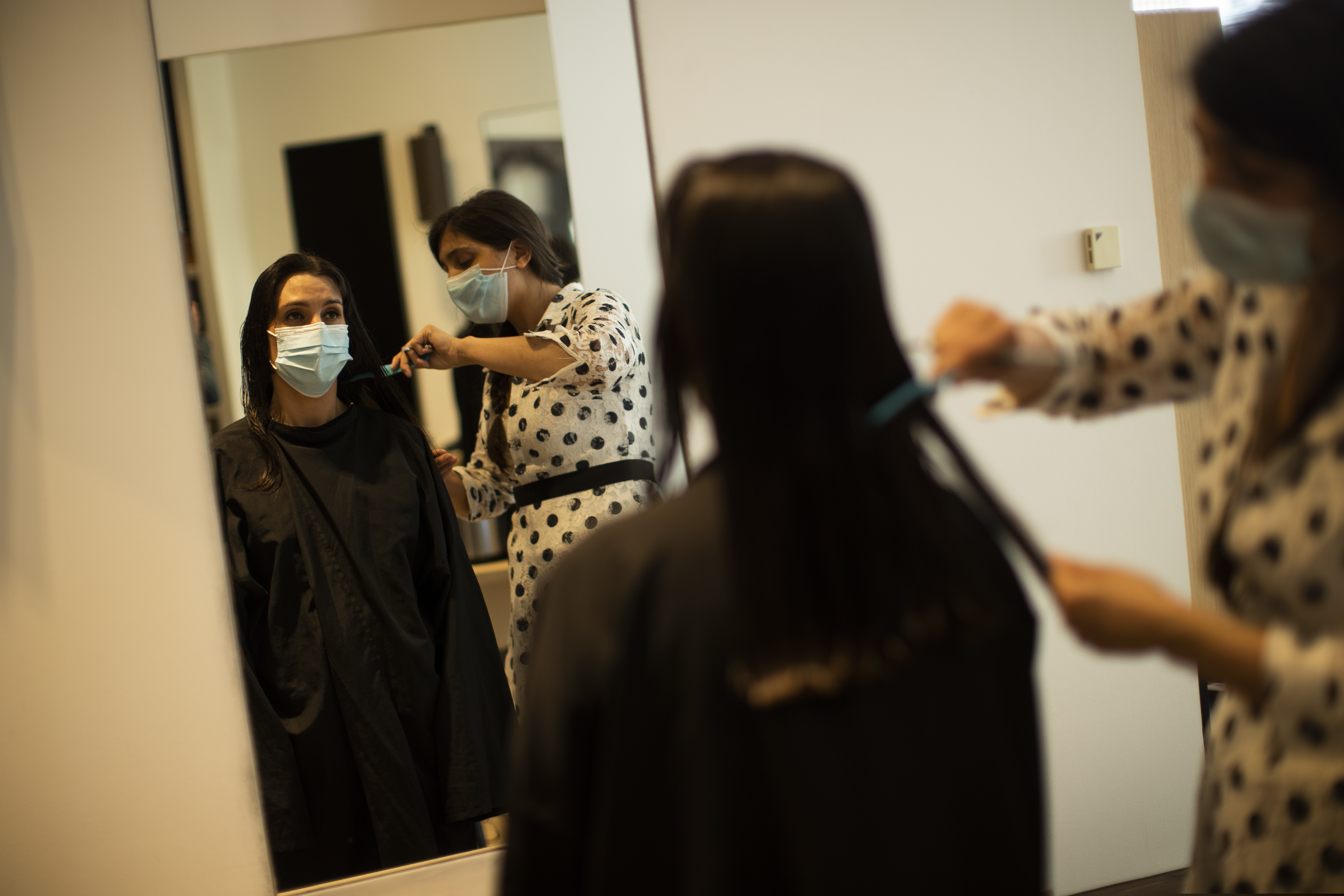 A client, wearing a mouth mask, gets her hair cut at the Maison L hair salon during the partial lifting of coronavirus, COVID-19, lockdown regulations in Brussels, Monday, May 18, 2020. Belgium is taking the next step in its relaxation of the coronavirus lockdown on Monday, with more students going to school, markets and museums reopening and the snip of a barber's scissors filling the air again. (AP Photo/Francisco Seco)