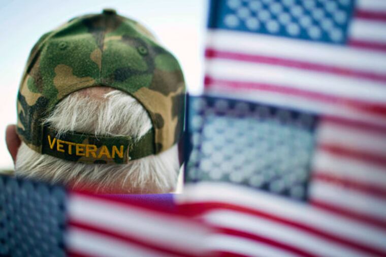 Frank Lindsey, wearing a veterans hat, is surrounded by flags as he attends a Veterans Day parade on Tuesday, Nov. 11, 2014, in Montgomery, Ala. (AP Photo/Brynn Anderson)