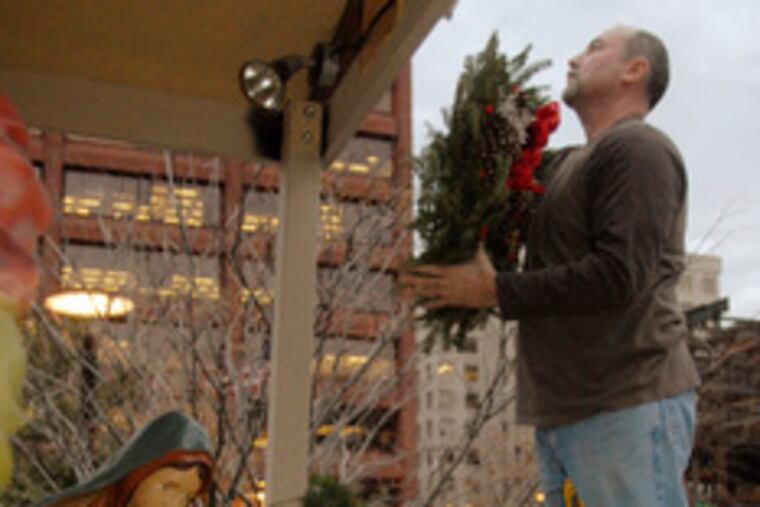 Ancient Order of Hibernians member Tony Nahill works on nativity display that was vandalized. Baby Jesus in photo is a loaner.