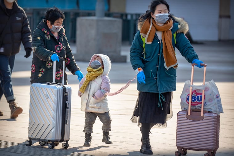 Travelers wear face masks as they walk outside the Beijing Railway Station in Beijing, Saturday, Feb. 15, 2020. People returning to Beijing will now have to isolate themselves either at home or in a concentrated area for medical observation, said a notice from the Chinese capital's prevention and control work group published by state media late Friday.