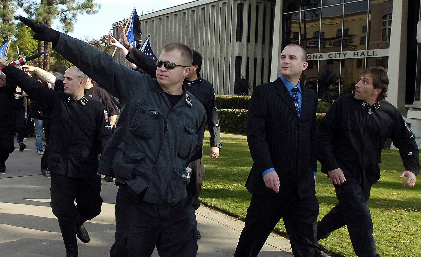 FILE-In this Saturday, Nov. 5, 2011, file photo, Jeff Schoep (second right in business suit), commander of the National Socialist Movement, leaves under police protection after a rally against illegal immigration in Pomona, Calif. One of the largest and oldest neo-Nazi groups in the U.S. appears to have an unlikely new leader: James Stern, a black activist who has vowed to dismantle it. Michigan corporate records indicate Stern replaced Jeff Schoep as the Detroit-based group's leader in January. (Thomas R. Cordova / The Orange County Register via AP)