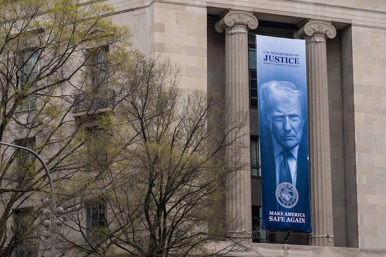 A banner bearing the face of President Donald Trump hangs from the Department of Justice building in March.