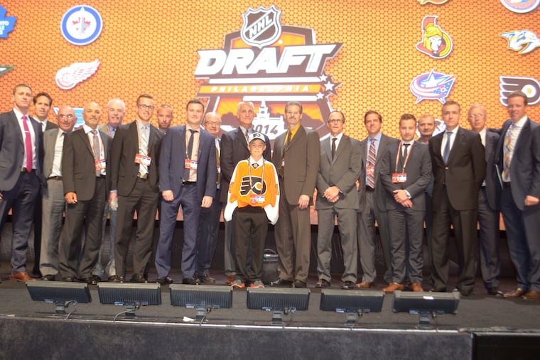 Ridly Greig (front, with Flyers jersey), then 12, was a "runner" who helped at the 2014 NHL draft in Philadelphia, and he is shown with club executives and scouts. Now he has a chance to be selected in the first round, perhaps by the Flyers.