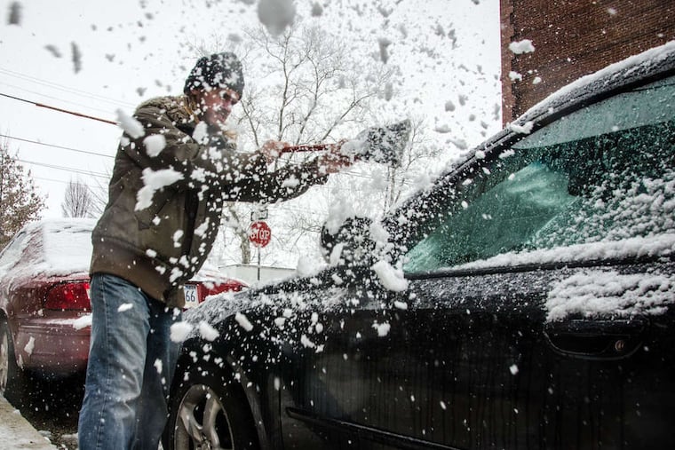 Alex Udowenko of West Philadelphia clears snow from his car. Totals of up to seven inches were reported throughout the region by evening. But the snow was not expected to stay around long.