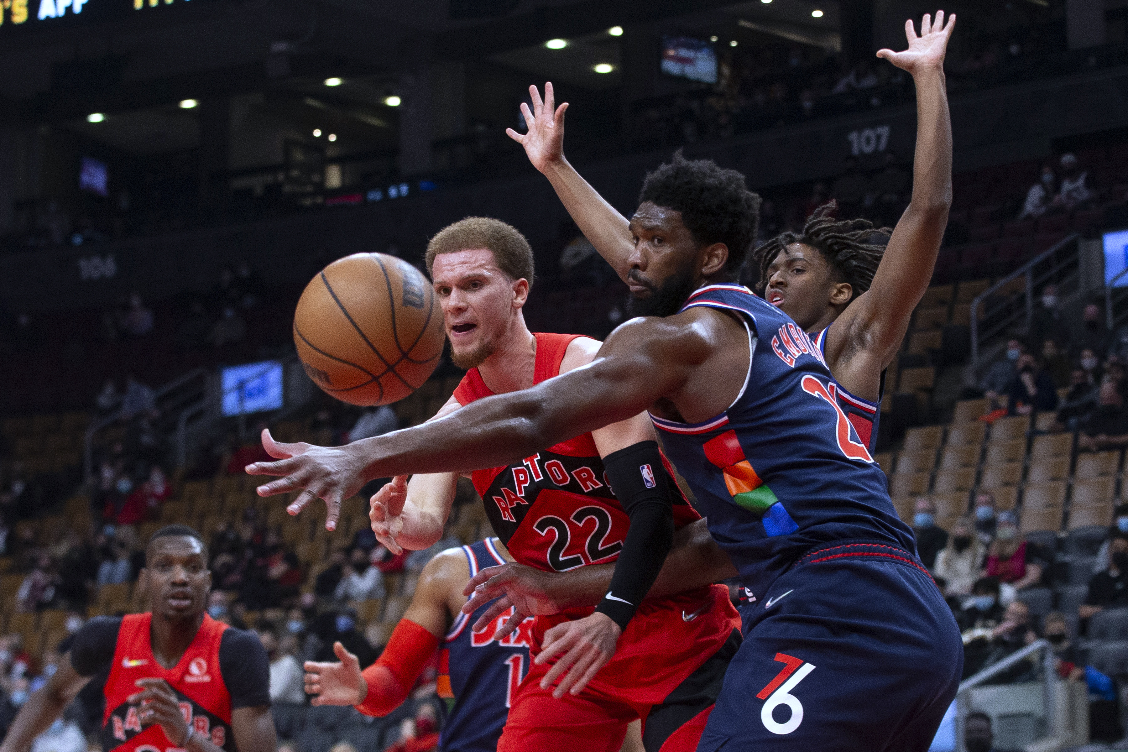 Toronto's Malachi Flynn passes the ball past 76ers center Joel Embiid during the first half.