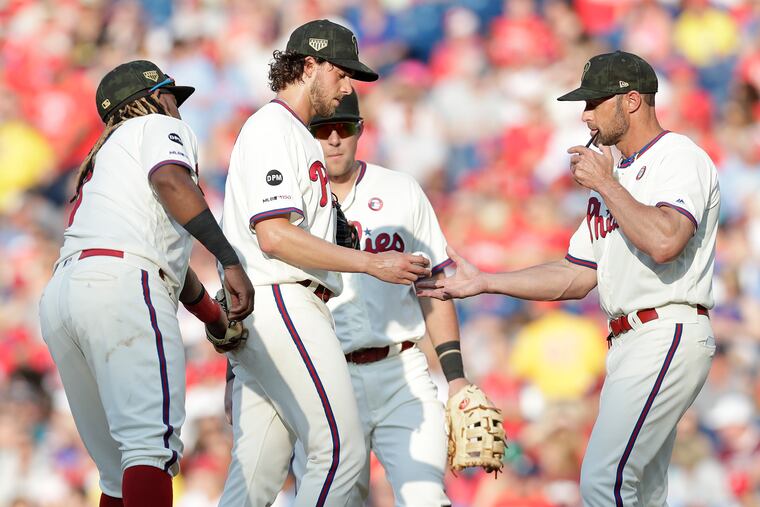 Aaron Nola (center) struggled earlier in the season. Now, he's back on track. But Gabe Kapler (right) still has problems.