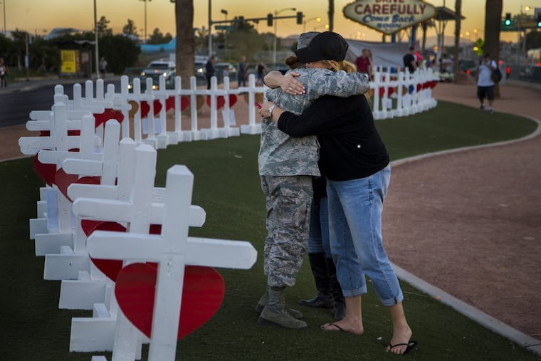 Sharon Black of Las Vegas, right, hugs Airmen First Class Williams of the U.S. Air Force after they were both overcome with emotion while viewing wooden crosses bearing the names of those killed during last month’s mass shooting.