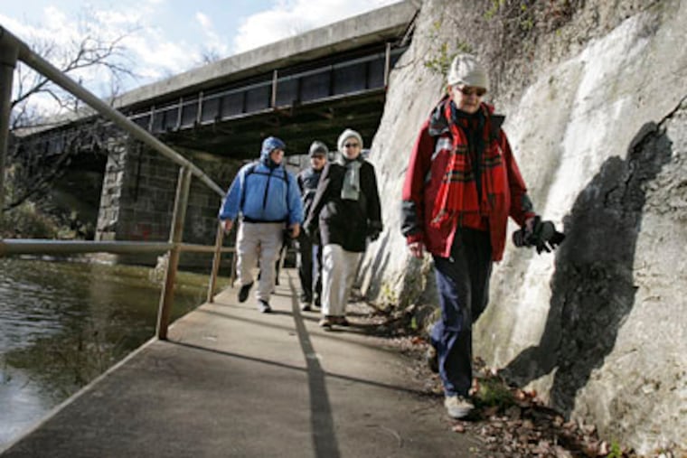 Norma Magargee of Mount Laurel (far right) and other members of her hiking group walk near a railroad trestle on Park Drive in Cooper River Park.