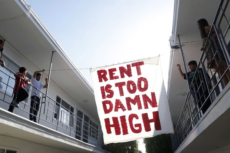 Organizers with Housing Long Beach, a local advocacy group pushing for rent control and eviction protections, hangs up a sign in the courtyard of an apartment complex on Cedar Avenue during a movie night they helped put on with tenants on June 15, 2018 in Long Beach, Calif.