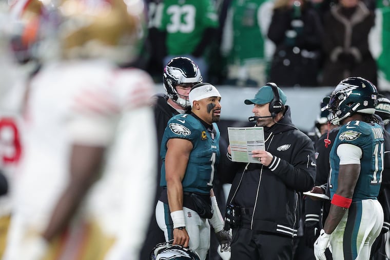 Eagles offensive coordinator Kevin Patullo, center, chats with quarterback Jalen Hurts, left, and wide receiver A.J. Brown in the fourth quarter of Sunday's loss.