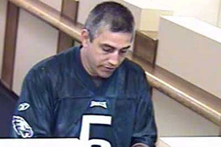 A suspect in the robbery of a bank branch in Northeast Philadelphia Tuesday examines a wad of cash handed over by a teller.