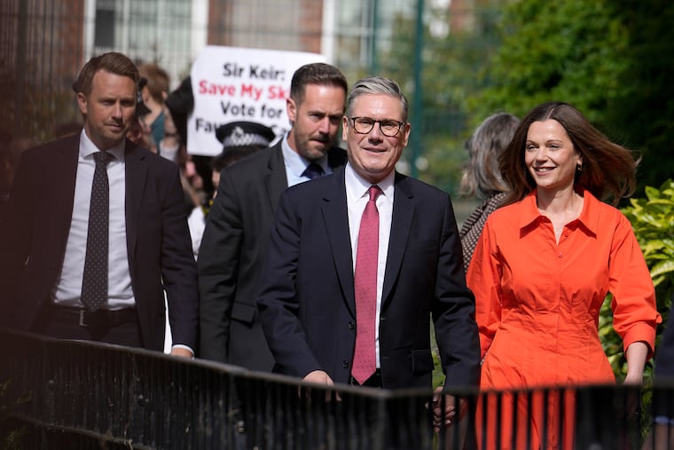 Labour Party leader Keir Starmer (center) and wife Victoria arrive at a polling station to cast their vote in London on Thursday. Starmer is likely to be Britain's next prime minister.