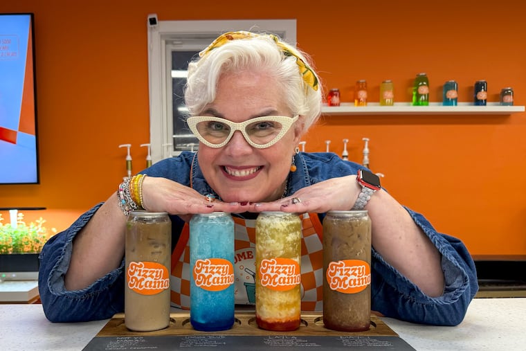Fizzy Mama owner Liz Hawkins poses with four cans of dirty soda, a Utah delicacy that combines soft drinks with coffee creamer and flavored syrup. The Bucks County shop offers around 150,000 flavor combinations, owner Liz Hawkins estimated.