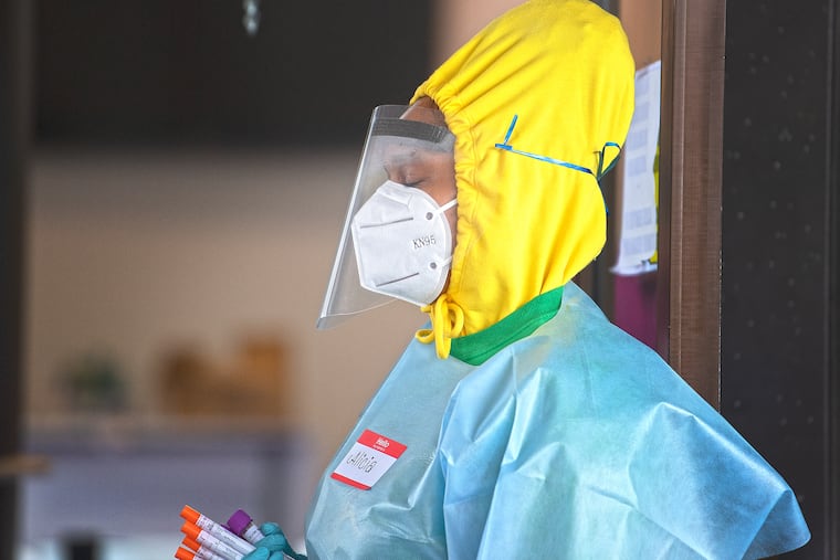 A health-care worker stands with Coronavirus test tubes at a testing site outside the Mount Airy Church of God in Christ in Philadelphia early in the pandemic.