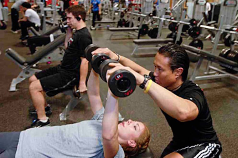 Tony Kim, a personal trainer at City Fitness on Spring Garden, helps Tiffany Buchert of Northern Liberties with her workout. (Ron Tarver/Staff)