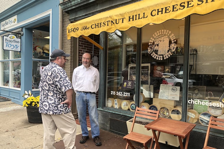 Dan Weiss (right) bids farewell to customer Dan Newton outside Chestnut Hill Cheese Shop, which Weiss’ father opened in 1963.
