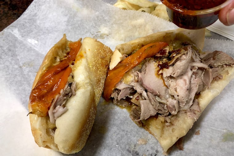 A pork and veal sandwich with long hot peppers gets topped with hot seeded oil at George's Sandwich Shop, 900 S. Ninth St.