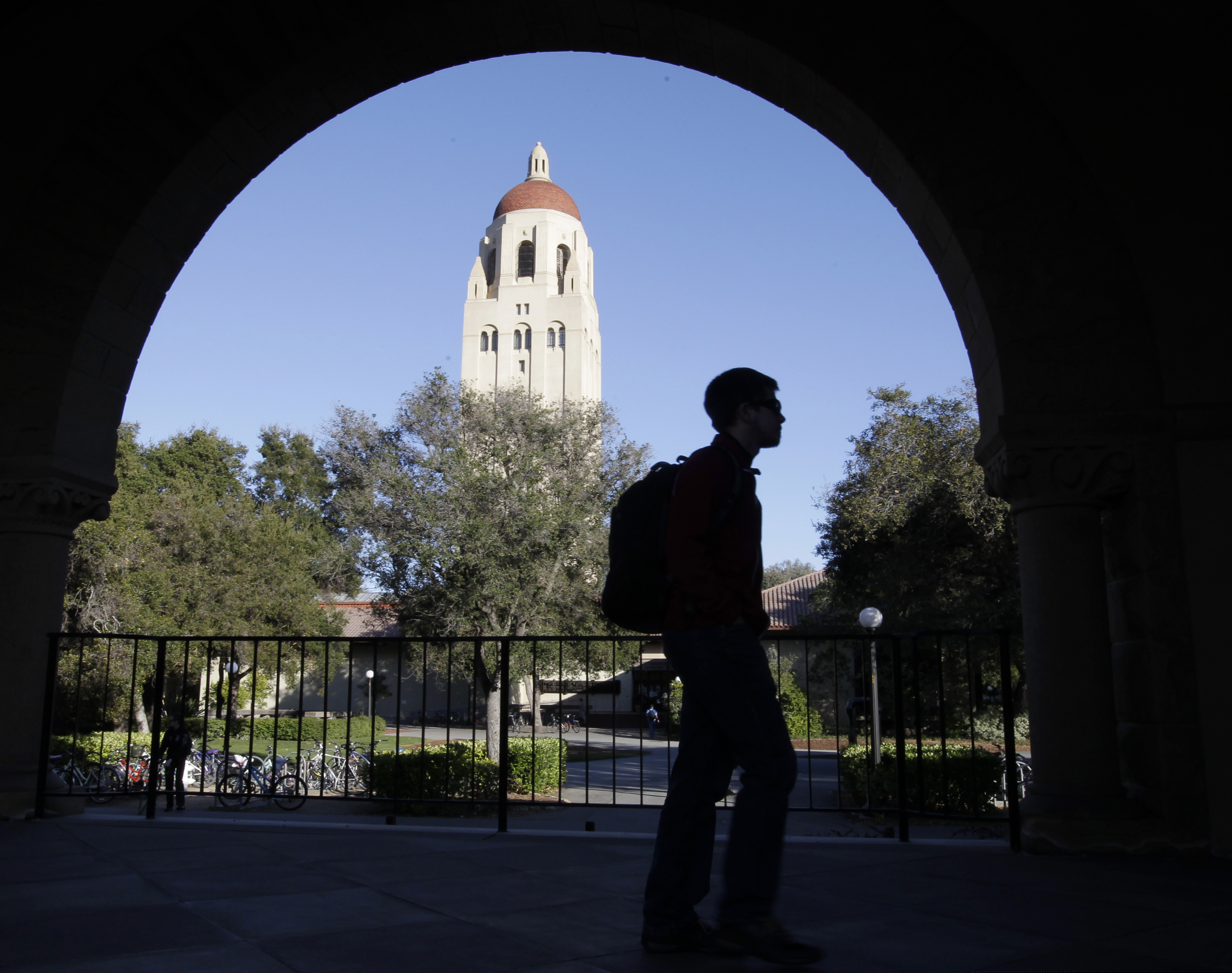 In this Feb. 15, 2012, file photo, a Stanford University student walks in front of Hoover Tower on the Stanford campus in Palo Alto, Calif. Federal authorities have charged college coaches and others in a sweeping admissions bribery case in federal court. The racketeering conspiracy charges were unsealed Tuesday, March 12, 2019, against coaches at schools including Stanford, Wake Forest, Georgetown, the University of Southern California and the University of Southern California, and UCLA. (AP Photo/Paul Sakuma, File)