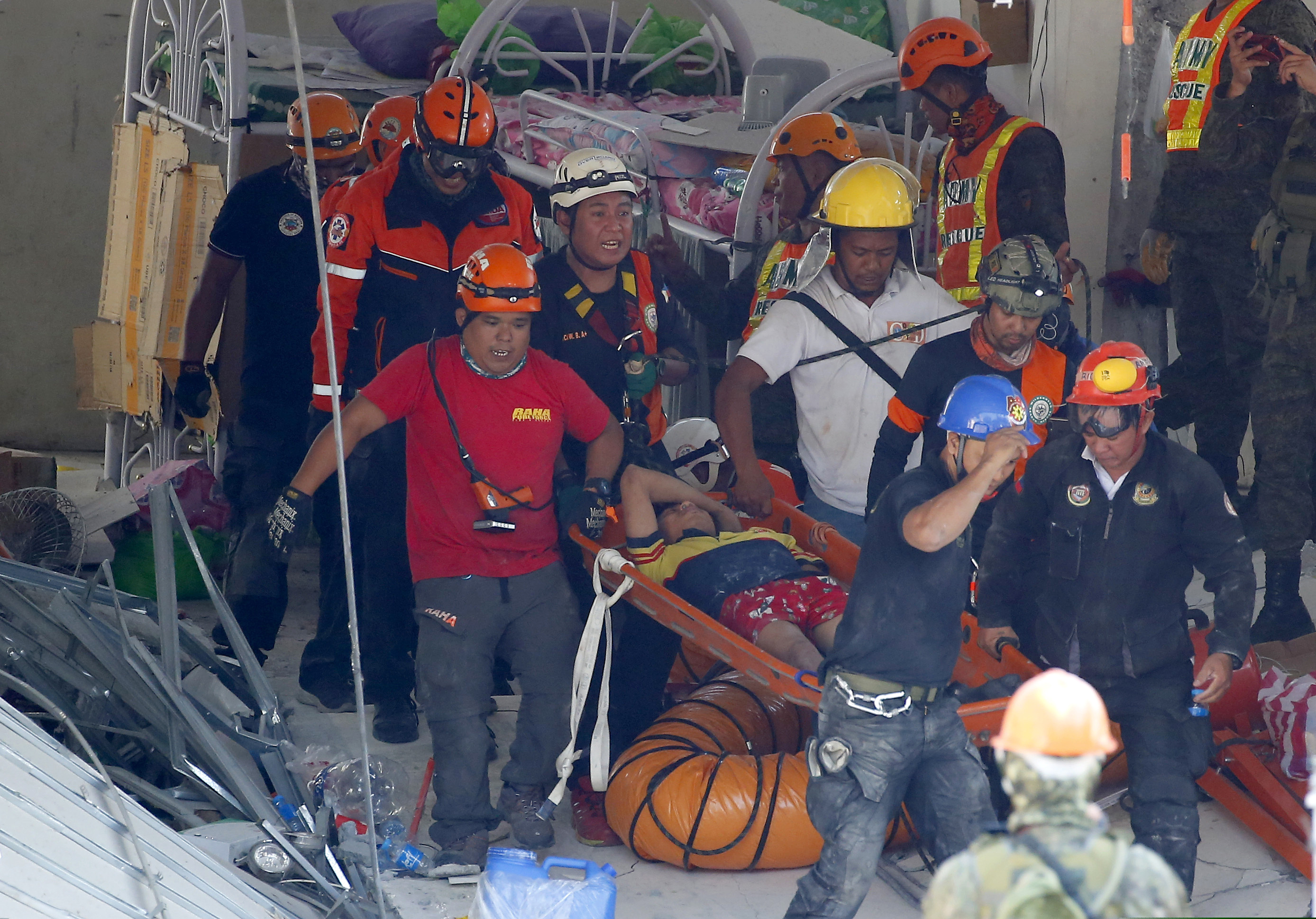 Rescuers carry an earthquake survivor after being pulled out from the rubble of a commercial building following Monday's 6.1 magnitude earthquake in Porac township, Pampanga province, north of Manila, Philippines, Tuesday, April 23, 2019.