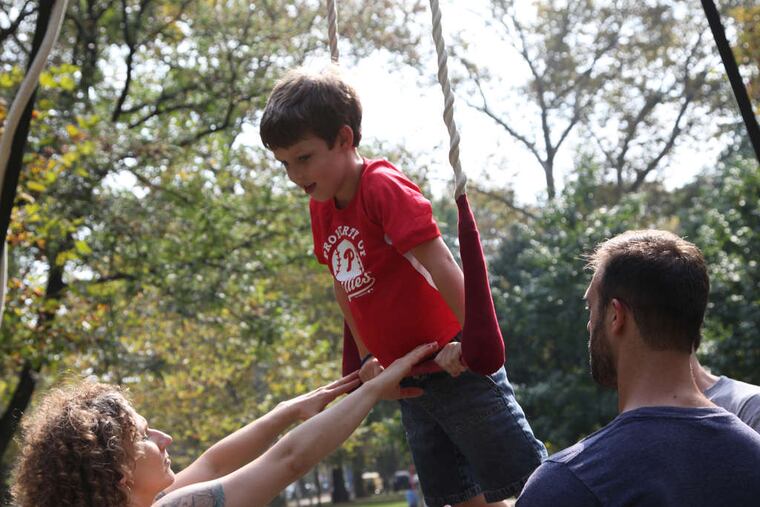 Cole McIntosh, 6, enjoys learning the trapeze from Erin Flanigan and Nick O'Kane of the Cotton Candy Circus during the city's first Figment festival at Clark Park in West Philadelphia.