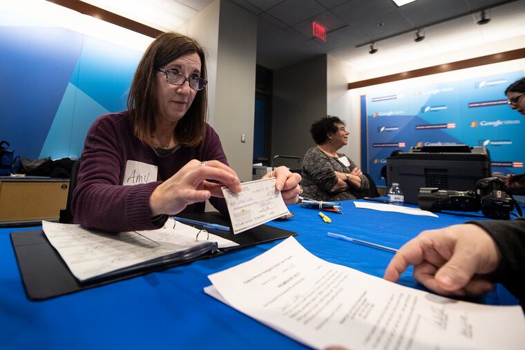 Amy Krulik, president of the Hebrew Free Loan Society of Greater Philadelphia, awards a no-cost, short-term loan check to an unidentified applicant Sunday at the National Constitution Center.