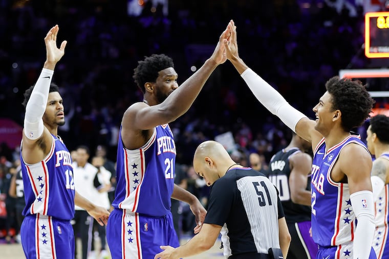Sixers center Joel Embiid celebrates his team's win over the Sacramento Kings with his teammates, right, guard Matisse Thybulle and left, forward Tobias Harris.