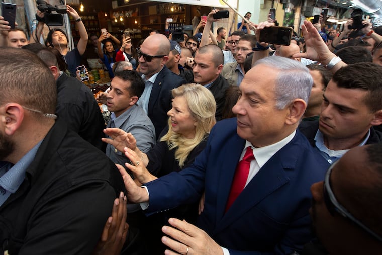 Israeli Prime Minister Benjamin Netanyahu, right, escorted by bodyguards walks with his wife Sara Netanyahu during a visit to the market on the eve of Israel's general elections in Jerusalem, Monday, April 8, 2019. (AP Photo/Sebastian Scheiner)