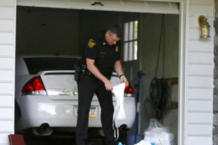 A Manheim Township police officer bags protective clothing after searching the house where three members of the Haines family (left) were killed. From top, they are Thomas, Lisa and their son, Kevin, 16.