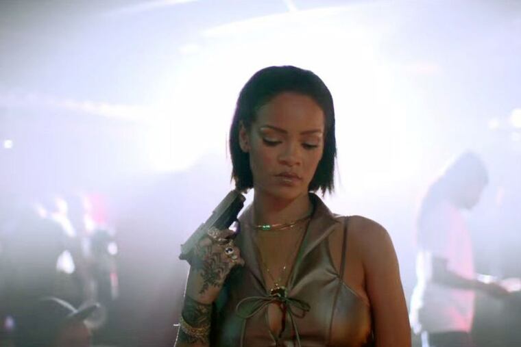 Screen shot from Rihanna's "Needed Me" video as she goes into a strip club carrying a pistol with apparent ill intent.