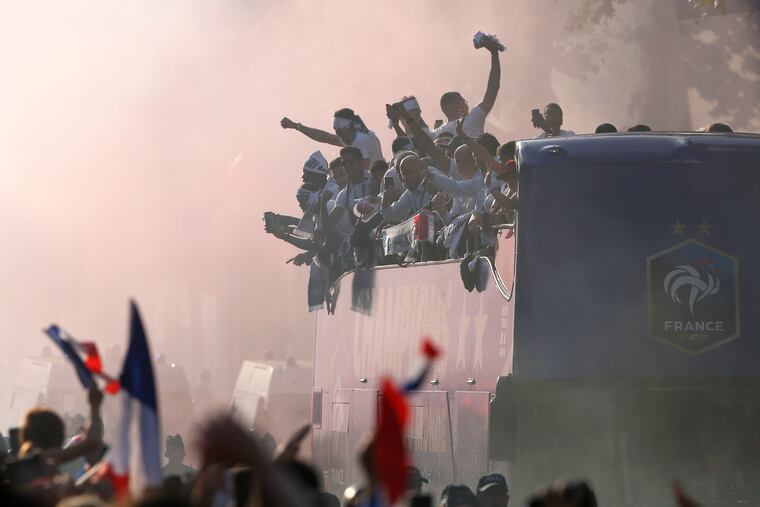 The crowd cheers France's victorious World Cup team descending in a bus upon Paris' packed Champs-Elysees avenue after the team's victory over Croatia.