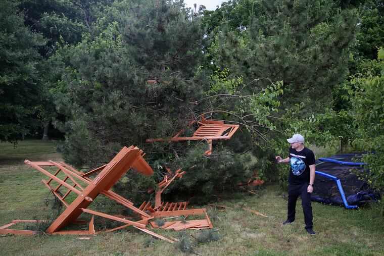 Matthew Melucci examines a trampoline and play set that blew into a neighbor's yard after tornado apparently touched down Thursday behind his home in Mullica Hill.