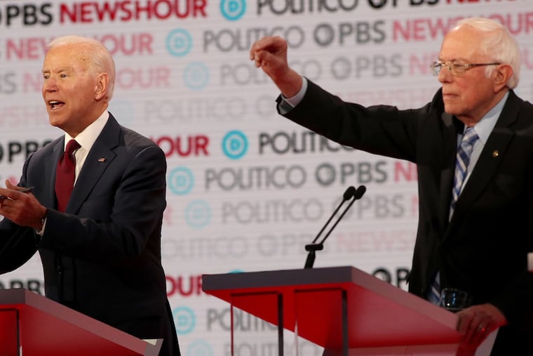 Democratic presidential candidate Sen. Bernie Sanders (I-Vt.), right, raises his hand as former Vice President Joe Biden makes a point during a Democratic presidential primary debate in December. Both candidates cancelled scheduled rallies in Cleveland Tuesday night.