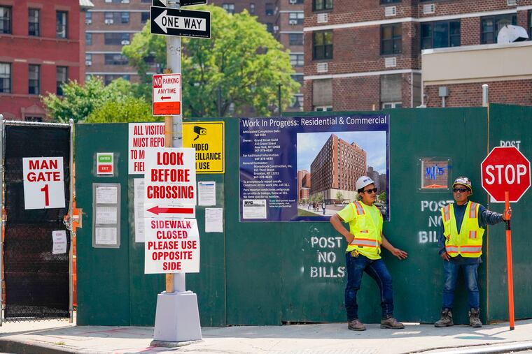 Construction workers help direct traffic outside a residential and commercial building under construction at the Essex Crossing development on the Lower East Side of Manhattan, Thursday, Aug. 4, 2022. America’s hiring boom continued last month as employers added a surprising 528,000 jobs despite raging inflation and rising anxiety about a recession.