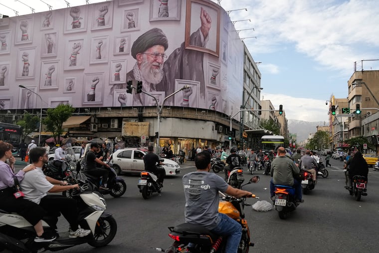 Motorbikes drive past a billboard with graphic showing the late Iranian Supreme Leader Ayatollah Ali Khamenei, who was killed in the U.S. and Israel strikes on Feb. 28, with his framed fist amongst his supporters framed fists in downtown Tehran, Iran, Wednesday, May 6, 2026.