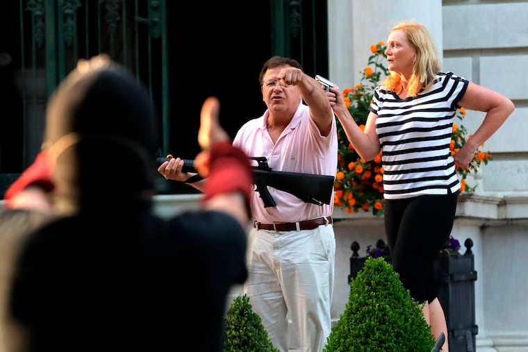 In this June file photo, armed homeowners Mark and Patricia McCloskey, standing in front their house along Portland Place confront protesters marching to St. Louis Mayor Lyda Krewson's house in the Central West End of St. Louis.
