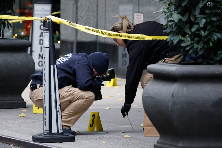 Members of the New York police crime scene unit photograph bullets lying on the sidewalk as they investigate the scene outside the Hilton Hotel in midtown Manhattan where Brian Thompson, the CEO of UnitedHealthcare, was fatally shot, Wednesday, Dec. 4, 2024, in New York.
