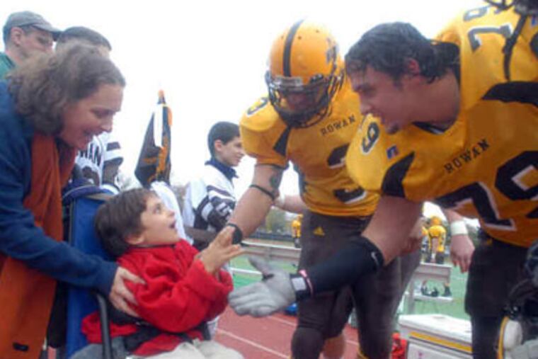 Luke DeFilippo and his mother, Laura, greet Rowan University football players at halftime. Luke met his teammates through the Friends of Jaclyn Foundation. (Ron Tarver / Staff Photographer)