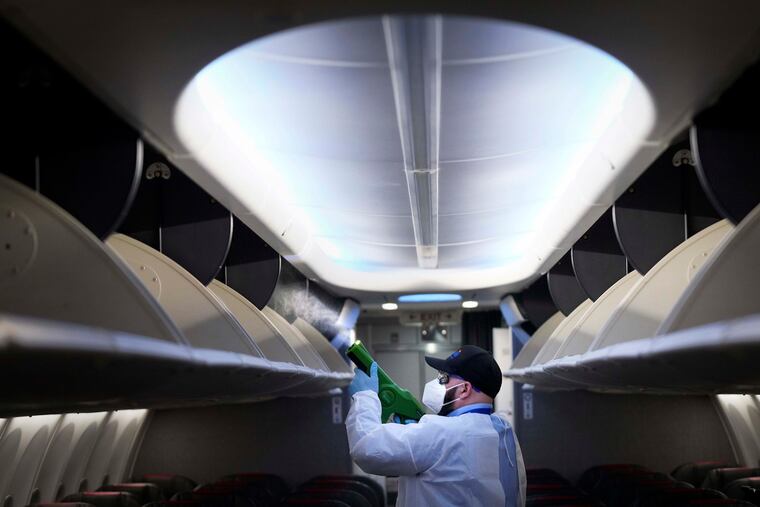 Jamie Shatinsky of ABM Aviation uses a handheld electrostatic disinfectant sprayer while disinfecting an American Airlines aircraft at DFW International Airport.