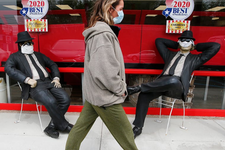 Barbara Mayer wears a mask walking to shop at Del Buono's Bakery and Carmen’s Deli in Stratford, New Jersey past the statues of mask wearing Blues Brothers movie characters. To stop the spread of the COVID-19 virus all shoppers must wear masks to enter essential businesses.