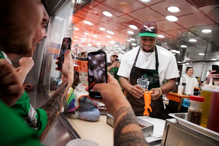 Eagles running back Saquon Barkley makes cheesesteaks at “Steakquon’s,” also known as Geno’s, on Monday after he was named the cover athlete for "Madden NFL 26."