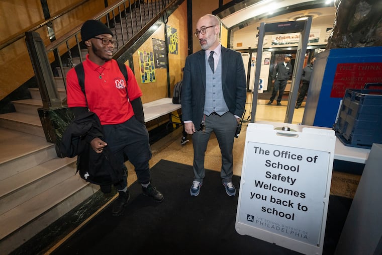 Mastbaum High School Principal David Lon, shown here greeting students and checking their phones in, is praised by readers for significant strides made at the school. Readers are less kind to the School District of Philadelphia.
