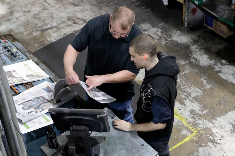 In this April 11 photo, pressmen Kit Stover, of Richmond, Mass. (left) and Lukus Ladeinde, of Pittsfield, Mass. check for correct registration of print from a sample of a newspaper fresh off the press at The Berkshire Eagle newspaper, in Pittsfield, Mass. The paper now features a new 12-page lifestyle section for Sunday editions, a reconstituted editorial board, a new monthly magazine, and the newspaper print edition is wider. That level of expansion is stunning in an era where U.S. newspaper newsroom employment has shrunk by nearly half over the past 15 years.
