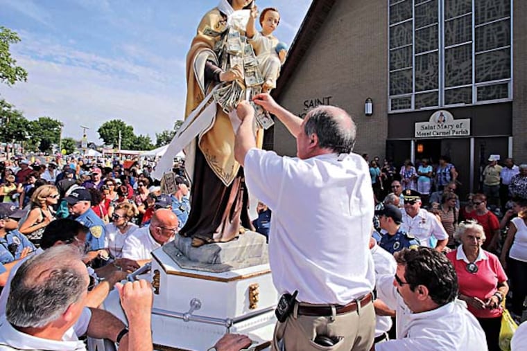 People flock to the Our Lady of Mt. Carmel statue and give money that Mount Carmel Society Treasurer Dave DeStefano of Hammonton pins on to the statue, which is always the last in the Parade of Saints at the 139th Our Lady of Mt. Carmel Festival in Hammonton on July 14, 2014. There is a carnival, food stand, beer garden and main stage entertainment. The Mount Carmel Society calls this the longest running Italian festival in the US since 1875. ( ELIZABETH ROBERTSON / Staff Photographer )