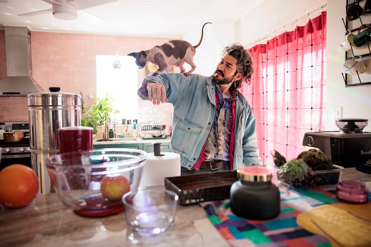 Franki Jupiter’s cat Nudo walks on his arm at home in Manayunk.