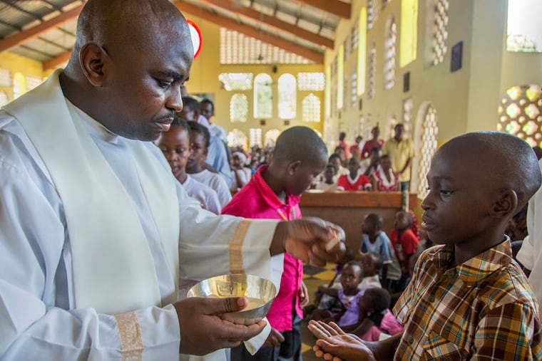 The Rev. Martin Karigu dispenses Holy Communion during Sunday Mass at St. Francis Xavier parish in Malindi, Kenya. (Georgina Goodwin / For the Philadelphia Inquirer)