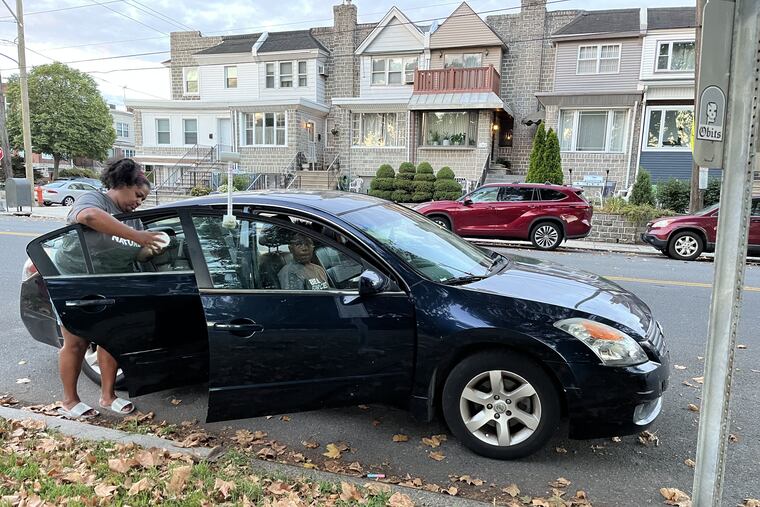 Meeka Outlaw attaches a pollution sensor to the rear passenger-side window of her Nissan Altima as part of an effort to collect data citywide on Saturday. The sensor records particulate matter. The sensor on the front collects temperature readings.